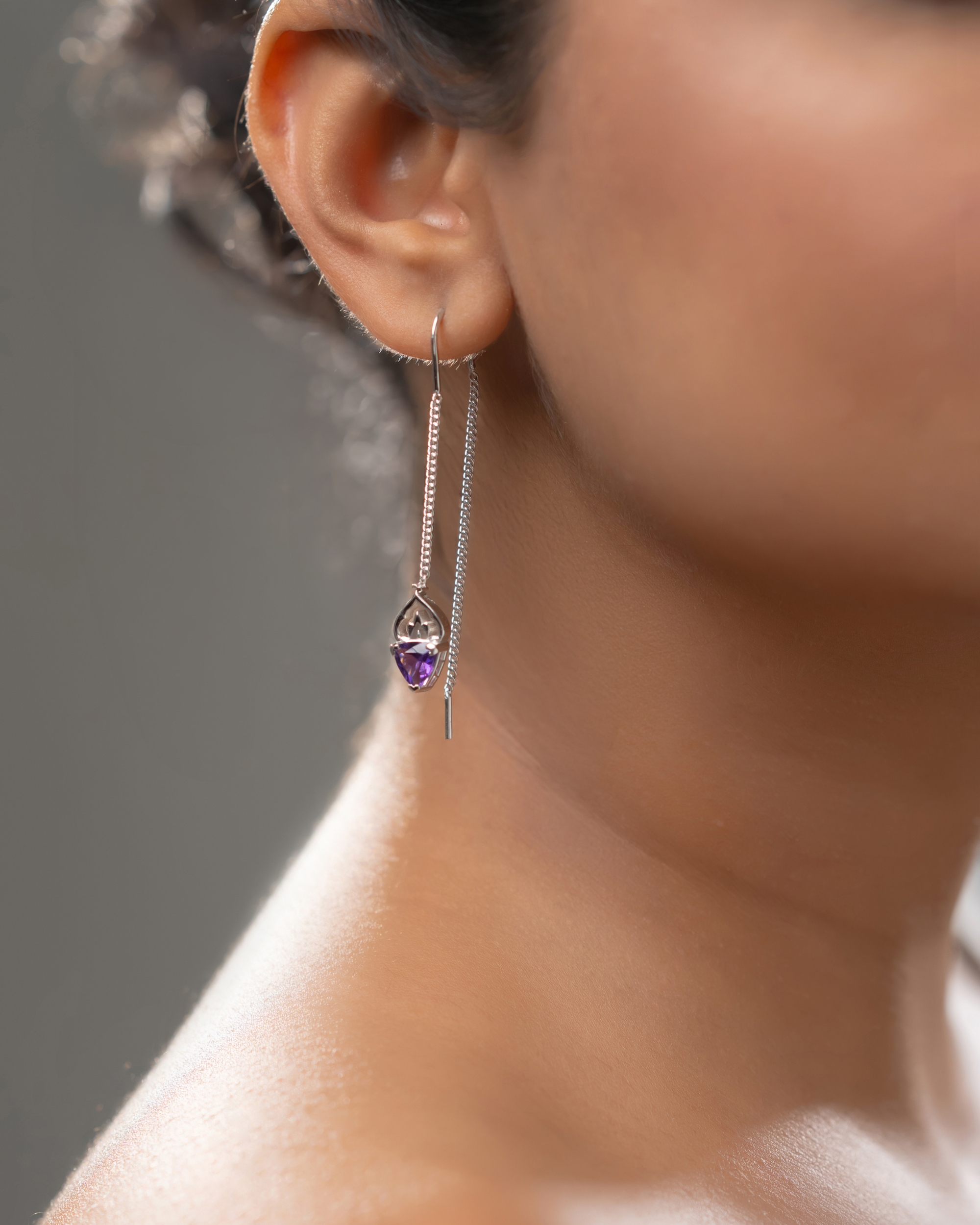 Close-up of a woman wearing handcrafted 925 sterling silver amethyst threader earrings with natural purple gemstones and elegant dangling chains.